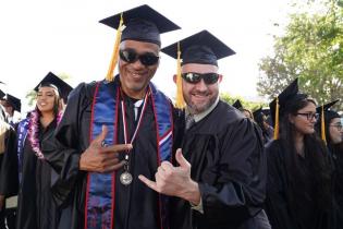 Two students embrace each other and smile for the camera during the annual Commencement ceremony.
